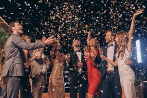 Group of beautiful people in formalwear having fun together with confetti flying all around